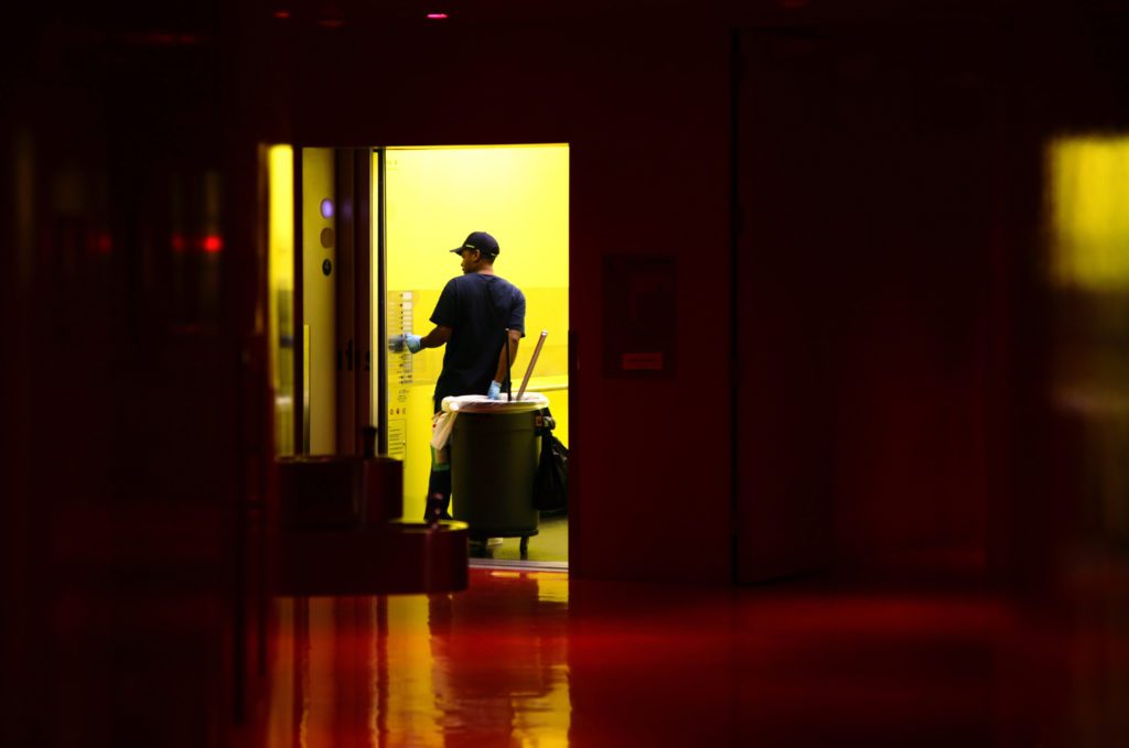 Janitor at elevator taking the trash bin to another floor